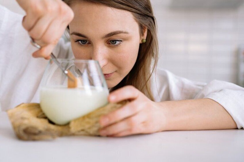 A person stirring a glass of milk on a wooden surface. 1