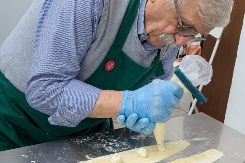A person in a green apron and blue gloves preparing dough on a table. 3