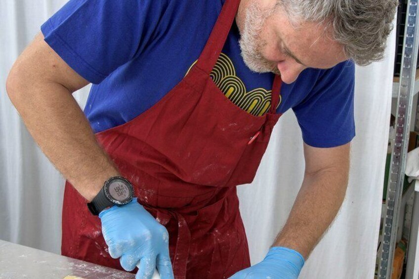 A person wearing a blue shirt and red apron, handling a white object. 4