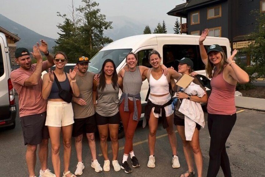A group of people standing in a parking lot with a van in the background. 1