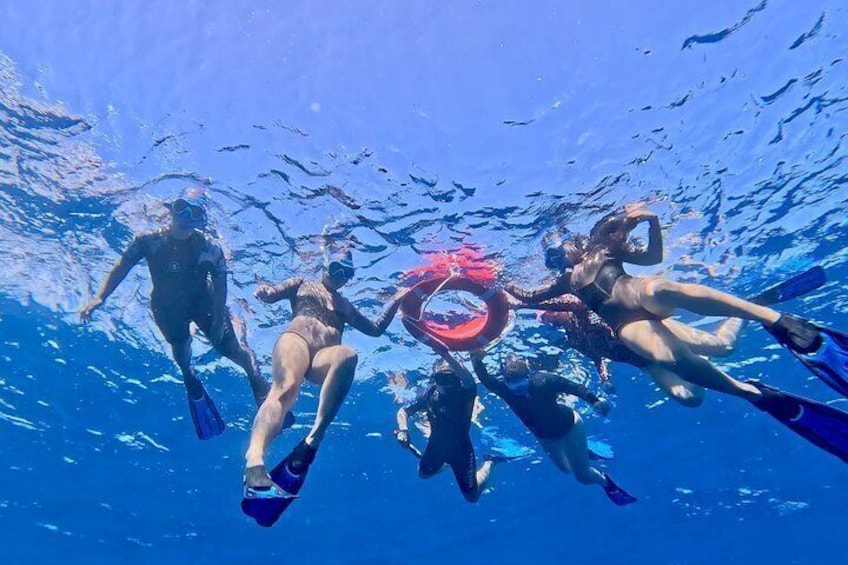 People scuba diving underwater with fins and a red circular object. 3