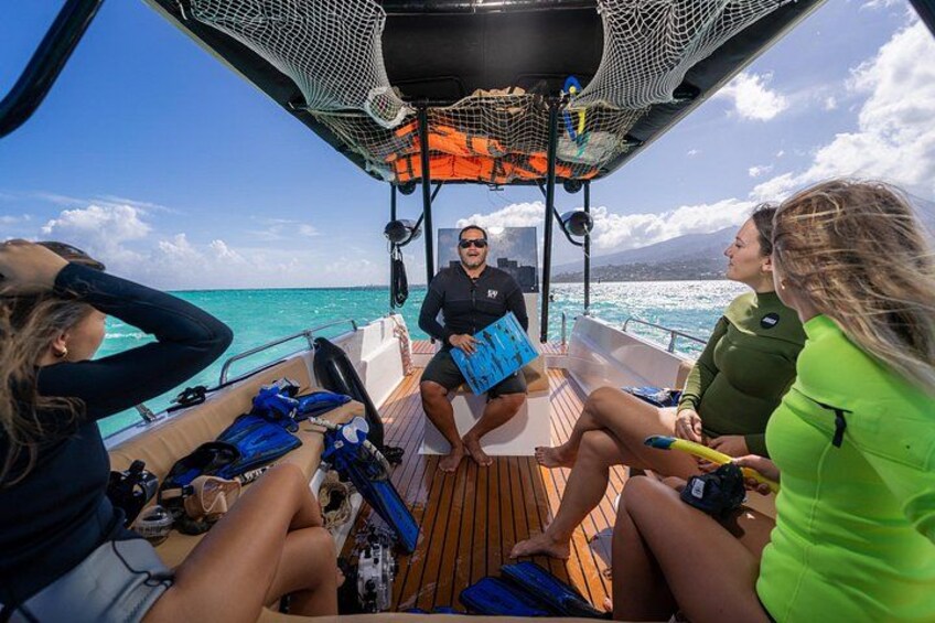 A boat with people sitting and standing, a netted area, and the ocean in the background. 5