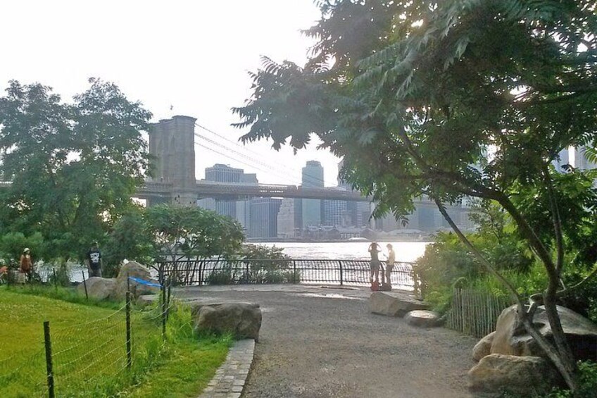 A park with a river, a bridge, and a city skyline in the background. 5