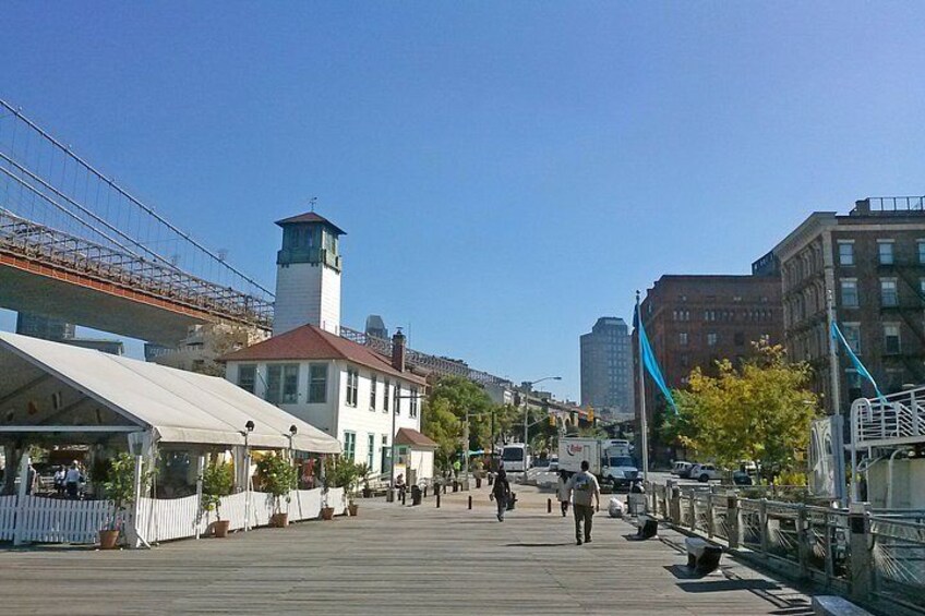 A boardwalk with buildings, a lighthouse, and a bridge. 3