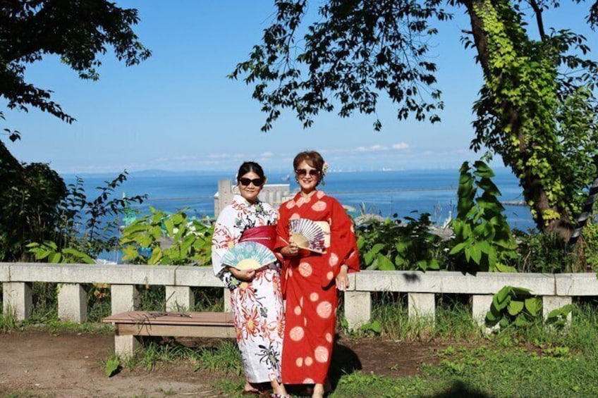 Two people standing by a railing with a view of the sea and greenery. 4