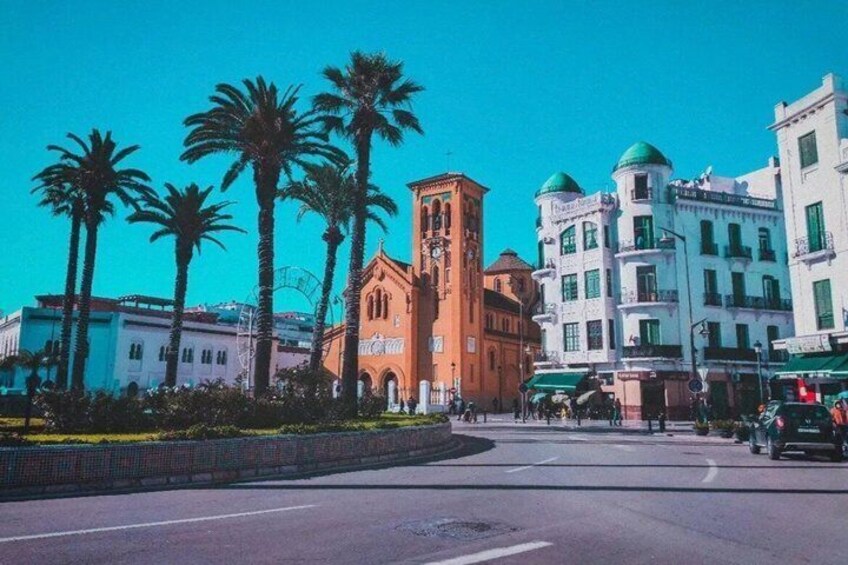 A street with palm trees, a church, and buildings with green domes. 1