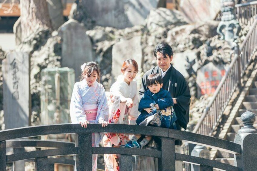 A family on a bridge with traditional attire, surrounded by stone structures and a staircase. 1
