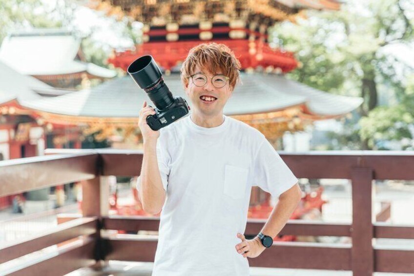 A person holding a camera in front of a traditional building with a red roof. 2