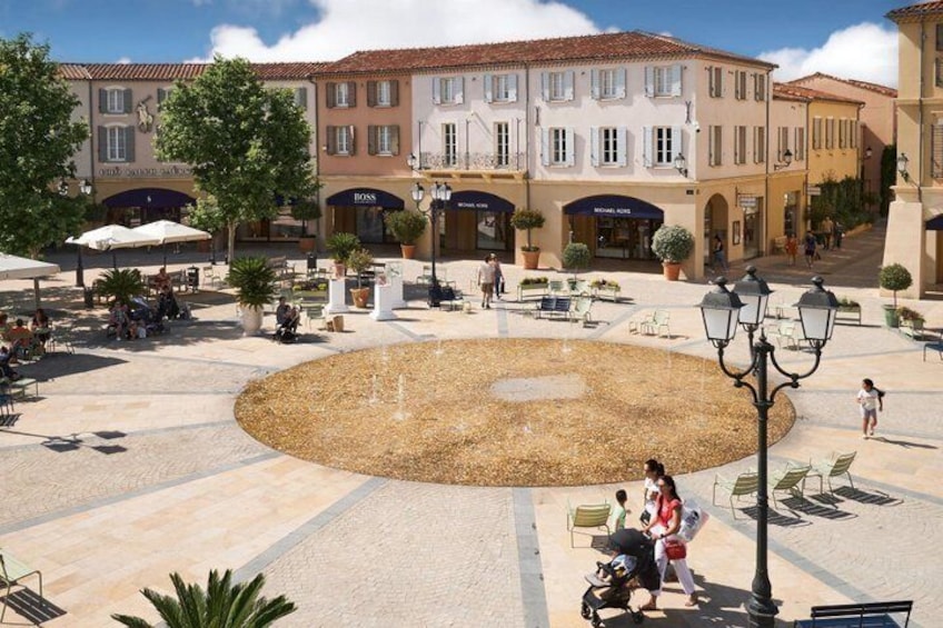 A public square with a fountain, seating areas, and surrounding buildings. 1
