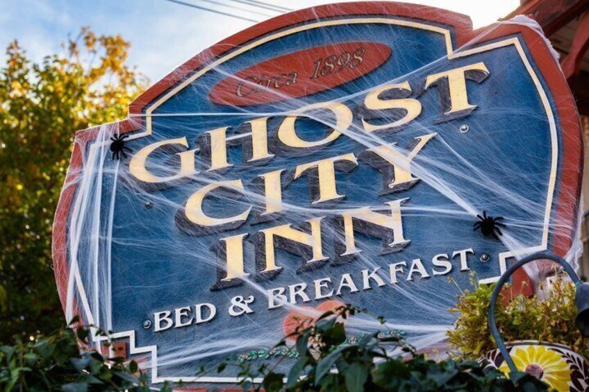 A sign for the Ghost City Inn with a spider decoration. 5