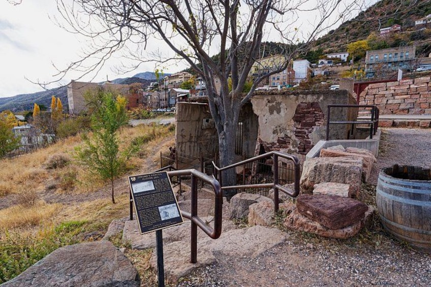 A historical site with ruins, a metal sign, and a tree. 2