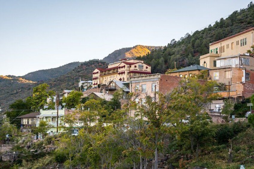 A hillside town with buildings, trees, and a mountain in the background. 2