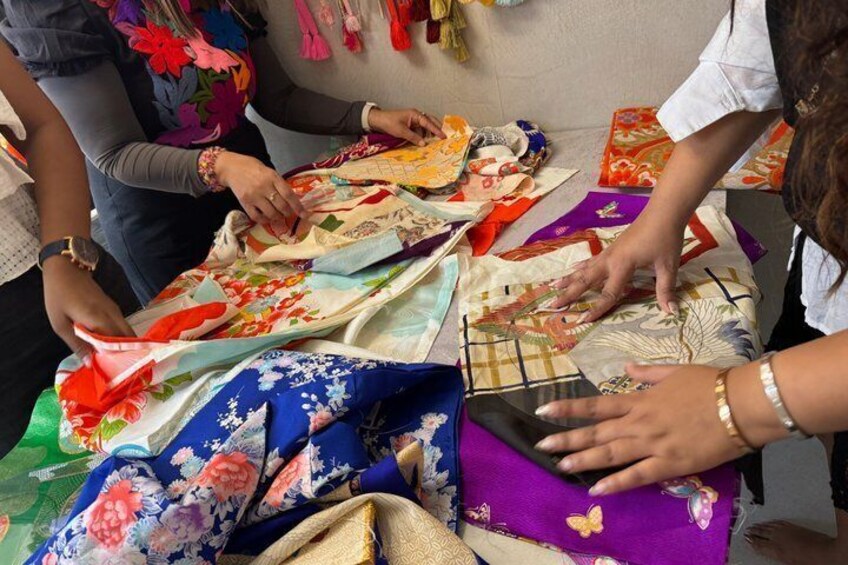 People examining colorful fabric patterns on a table. 1