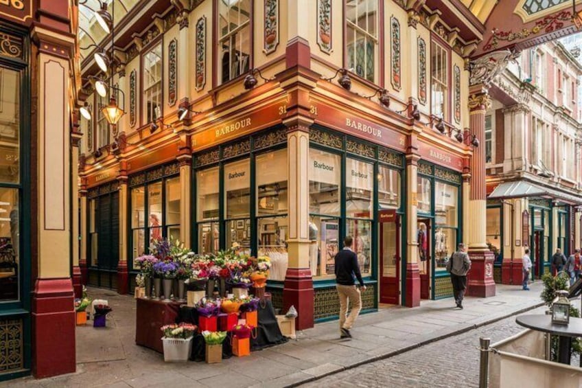 A street with a row of shops, including a Barbour store, and flower stalls. 5