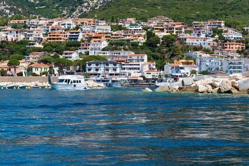 A coastal town with buildings, boats, and rocky shoreline. 3