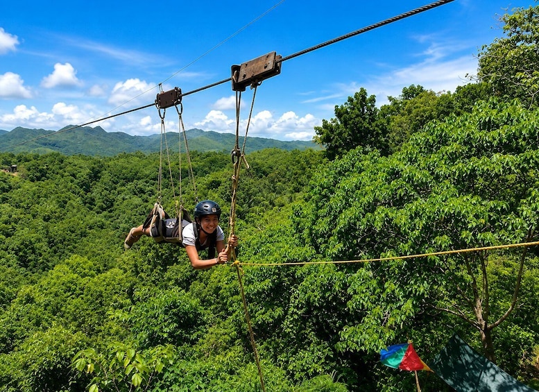 A person on a zip line over a forested area with mountains in the background. 2
