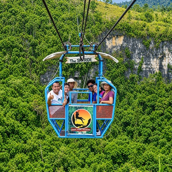 A cable car with passengers, labeled 'The Skyride,' suspended above a lush green landscape with cliffs. 3