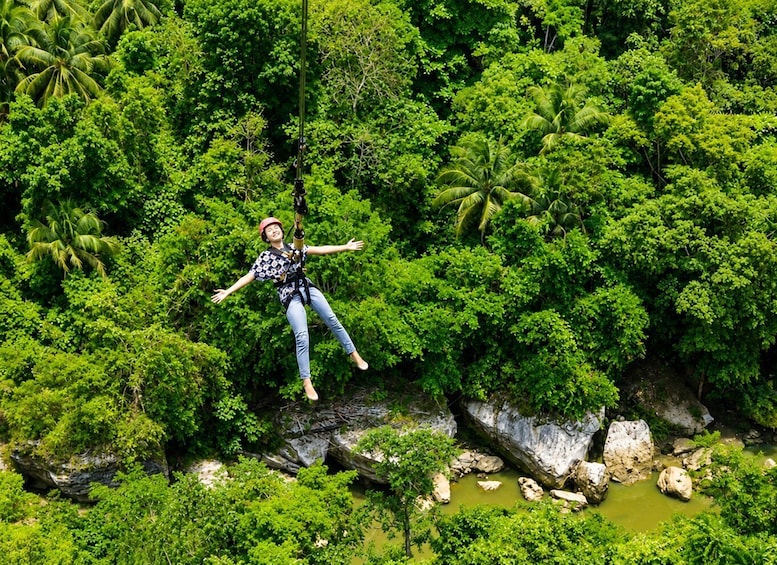A person bungee jumping from a cliff surrounded by lush greenery. 1