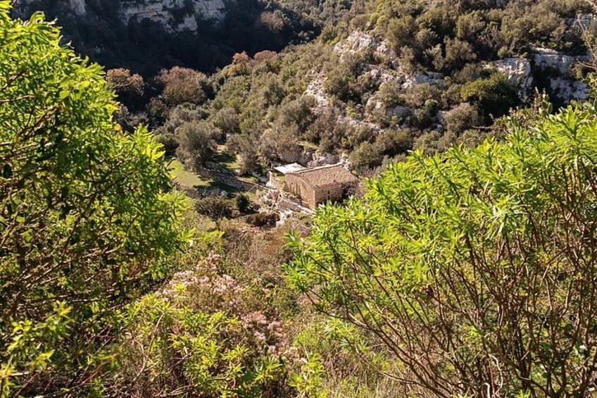 A mountainous landscape with a stone building surrounded by dense vegetation. 2