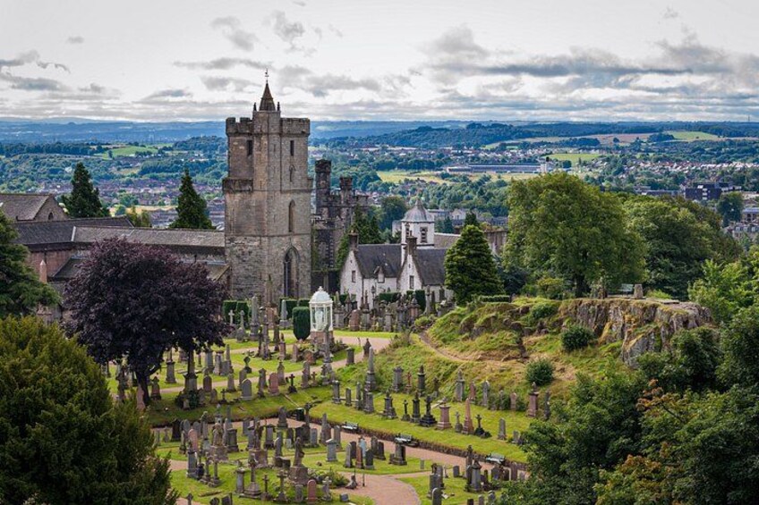 A historic castle with a tower, surrounded by a cemetery and lush greenery. 5