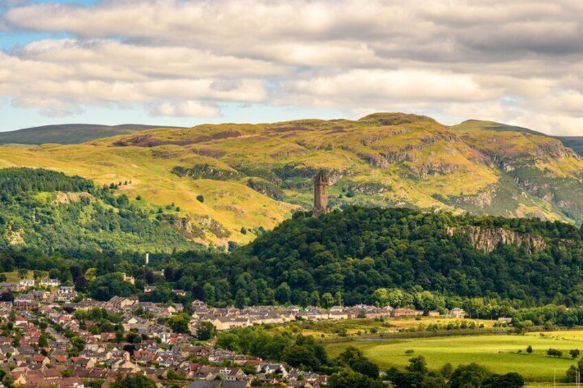 A valley with a prominent tower, lush green hills, and a small town. 5