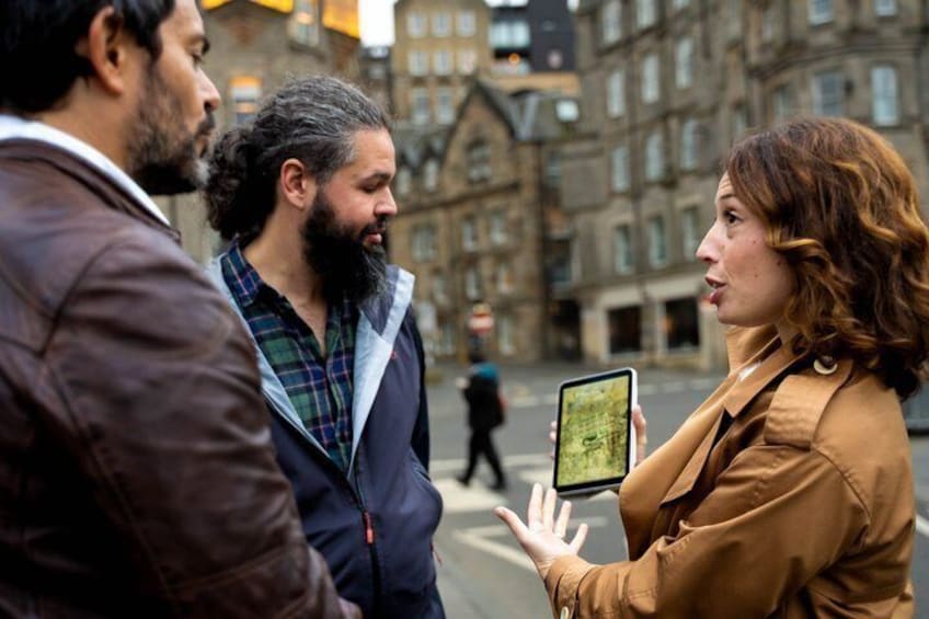 A person holding a tablet, standing in an urban street with historic buildings in the background. 2