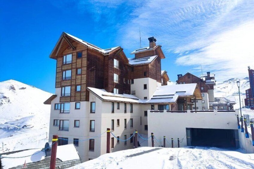 A snow-covered mountain resort with wooden buildings and a clear blue sky. 2