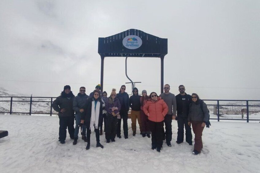 A group of people standing in a snowy area with a sign in the background. 5