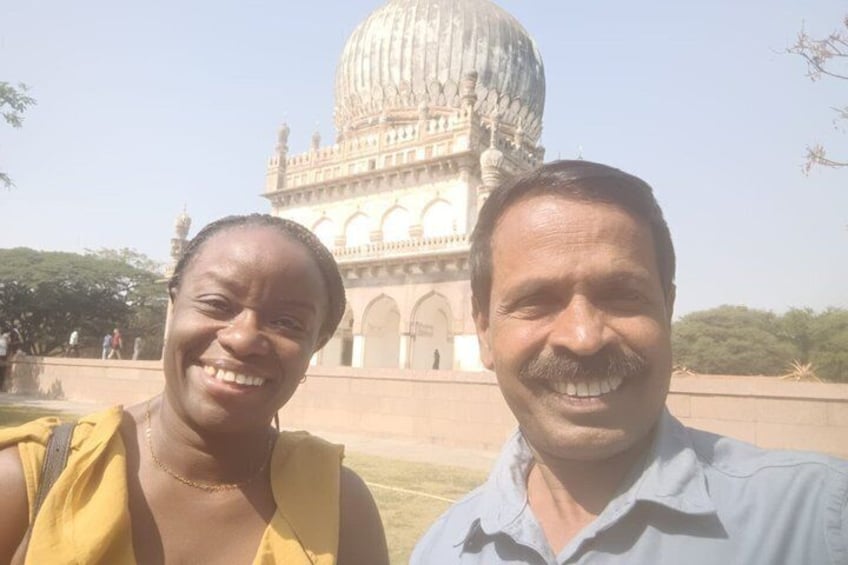 Two people standing in front of a large domed building with arches and columns. 3