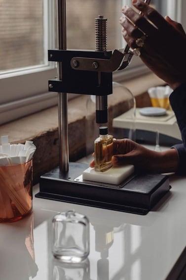 A person using a hydraulic press on a small bottle. 1