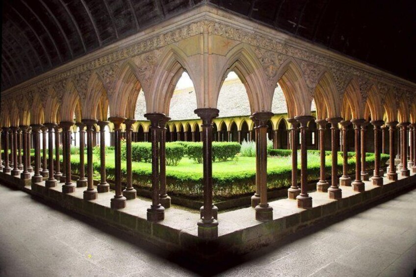 A cloister with a series of arches and columns, a central garden, and a stone pathway. 3