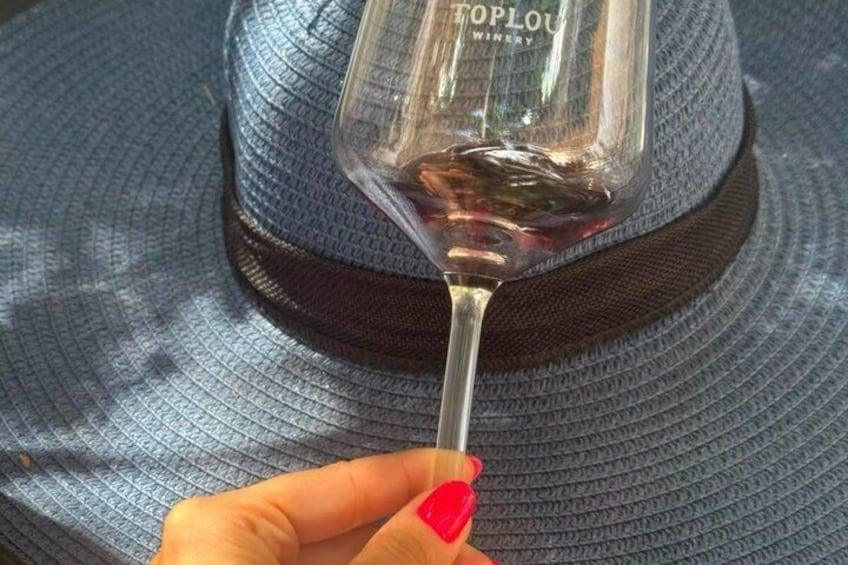 A hand holding a wine glass with a label that reads 'Toplou Winery.' 3