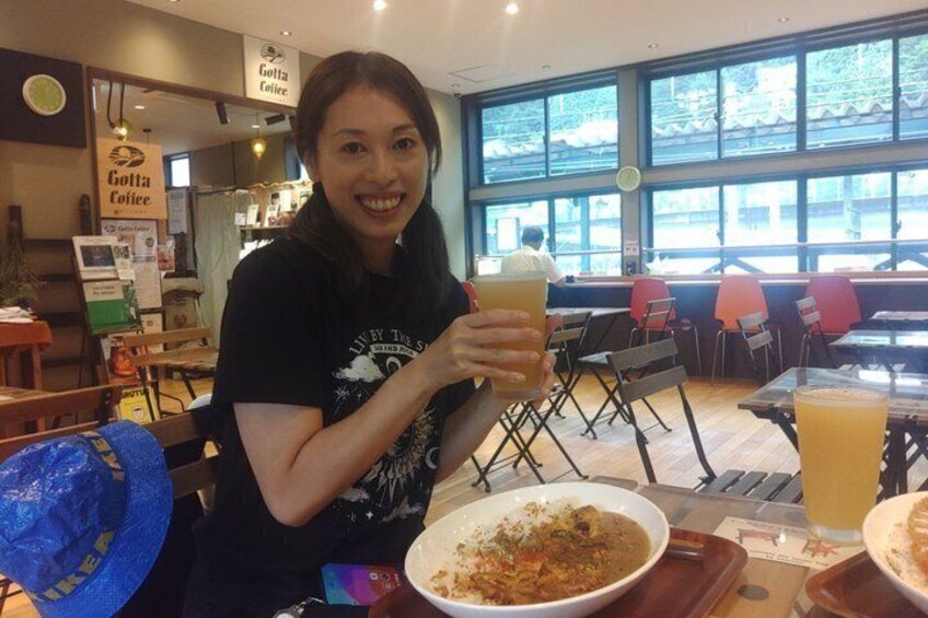 A person sitting at a table with a drink and a bowl of food in a cafe with large windows. 1