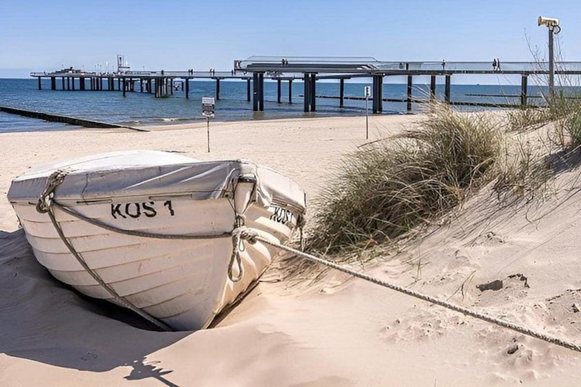 A boat named KOS 1 tied to a sandbank near a pier. 3