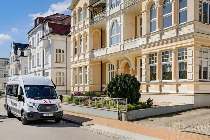 A white van with the number 31 parked on a street in front of a large, ornate building with balconies and arched windows. 1