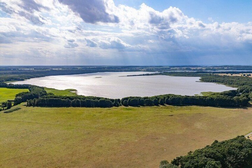 A large body of water surrounded by green fields and trees. 5