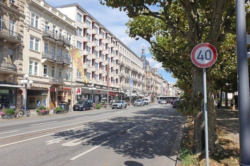 A street with a speed limit sign, buildings, and parked cars. 3