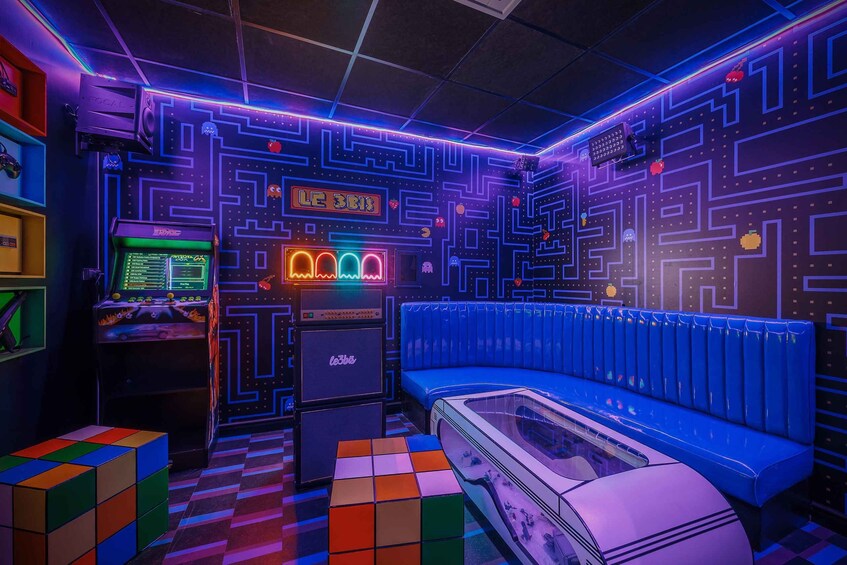 A retro-themed room with neon lights, a blue couch, a Rubik's cube, and a gaming console. 3