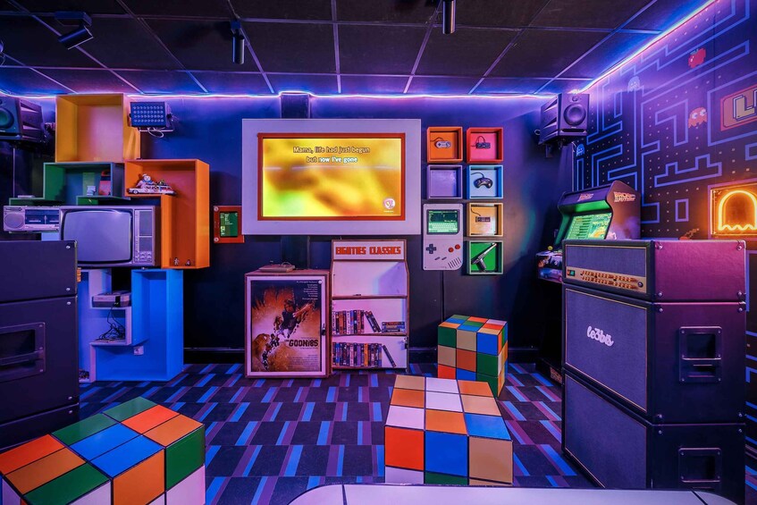 A retro-themed room with colorful tiles, a vintage TV screen, and various gaming consoles. 1