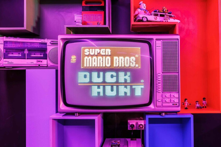 A retro television displaying 'Super Mario Bros. Duck Hunt' with vintage audio equipment and toys in the background. 4