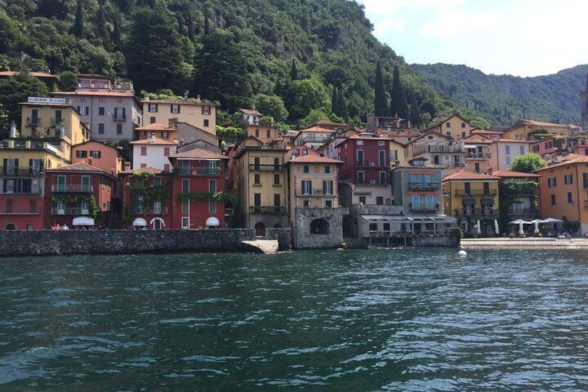 A coastal village with colorful buildings, a stone wall, and a boat docked near the shore. 3