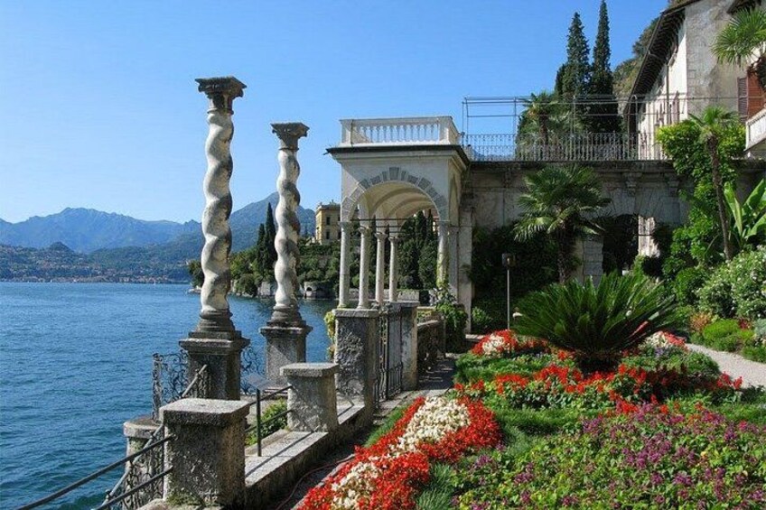 A coastal garden with stone balustrades, a fountain, and colorful flowers. 5
