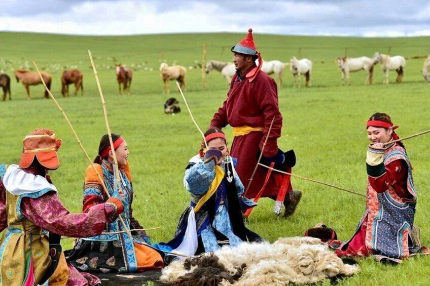 A group of people in traditional attire herding sheep in a grassy field. 2