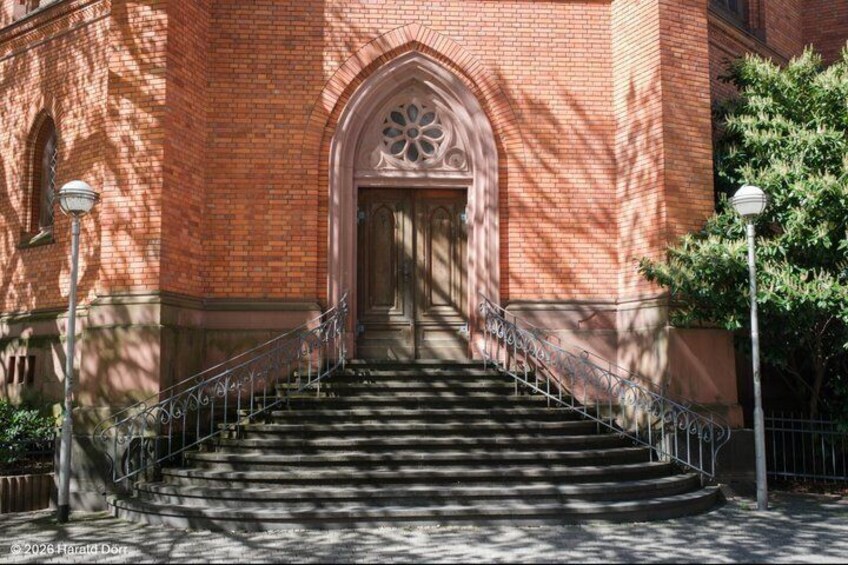 A brick building with a large arched entrance and a staircase leading up to it. 2