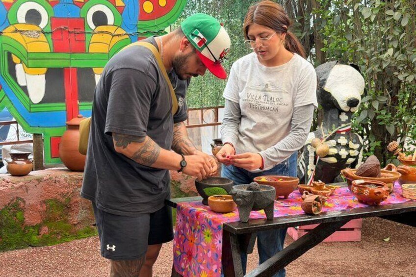 Two people at an outdoor market with pottery and a colorful mural in the background. 3
