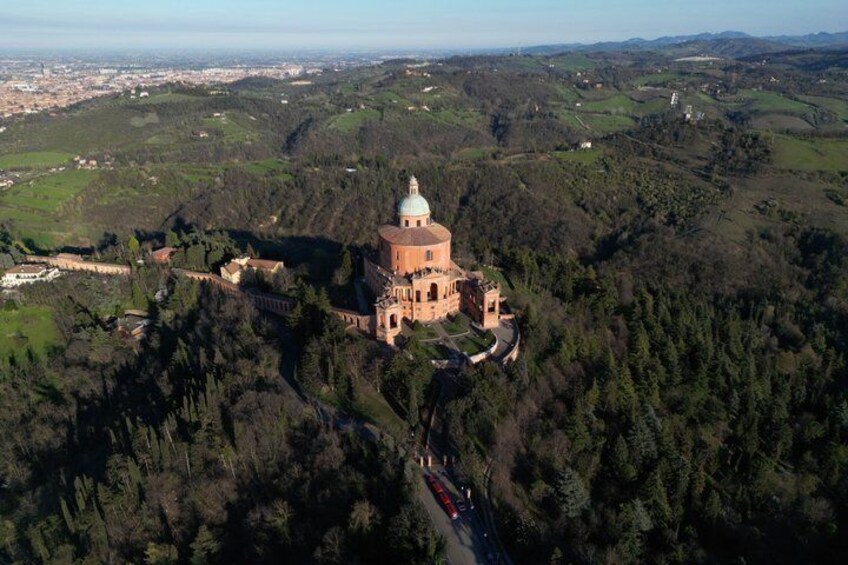 An aerial view of a historic building with a dome, surrounded by dense forest and rolling hills. 4