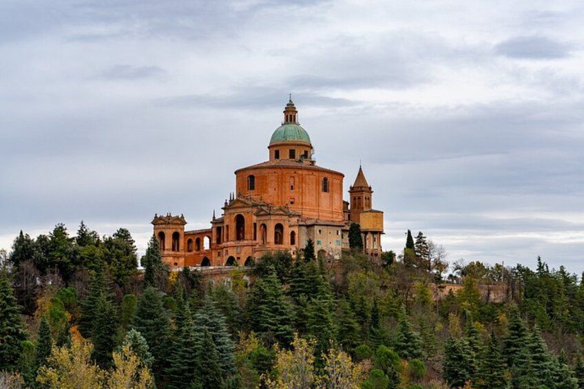 A large, historic building with a dome and multiple towers, surrounded by dense forest. 1