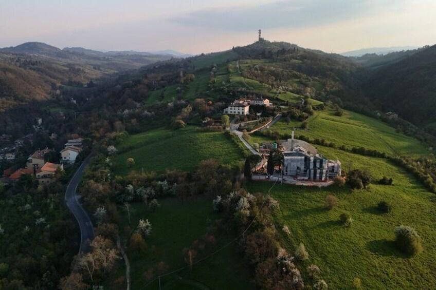 A valley with a winding road, green fields, and a hilltop with a tower. 2