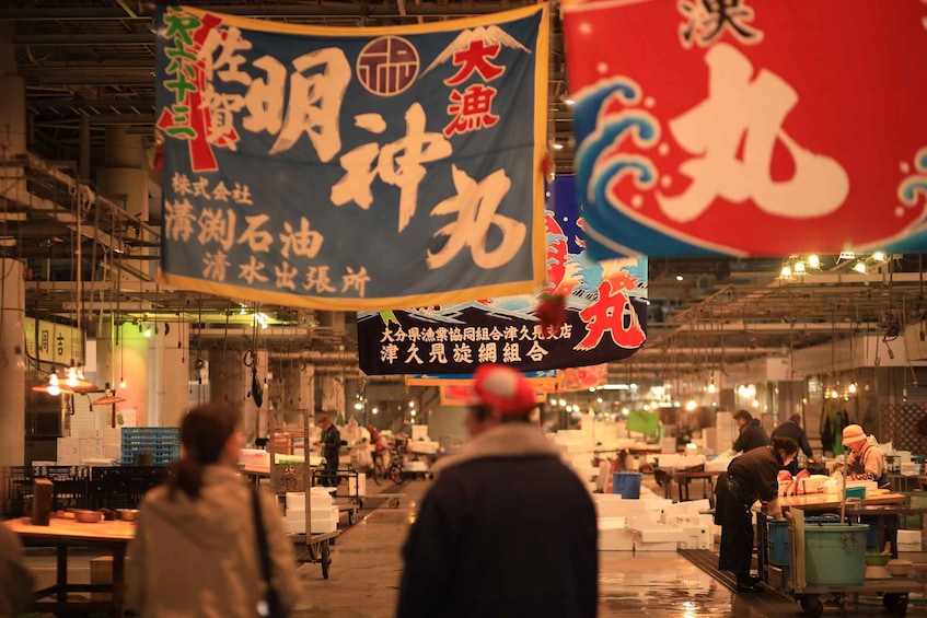 A bustling indoor market with various stalls and hanging banners. 5