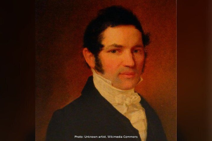A portrait of a person with a dark coat and white shirt, set against a plain background. 5